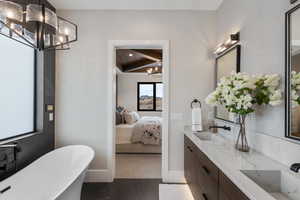 Ensuite bathroom with a chandelier, a freestanding tub, double vanity, and baseboards