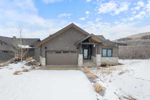 View of front of property featuring a garage, stone siding, and driveway