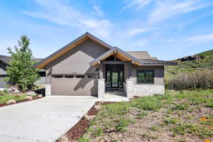 View of front of home featuring a garage, stone siding, and concrete driveway