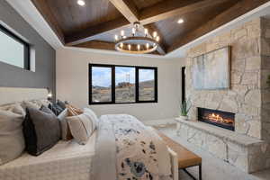 Carpeted bedroom with wood ceiling with exposed beams, a chandelier, baseboards, a stone fireplace, and coffered ceiling