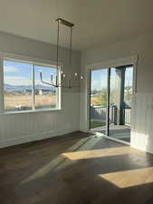 Unfurnished dining area with dark wood finished floors, a chandelier, plenty of natural light, and a mountain view
