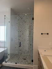Bathroom featuring vanity, a soaking tub, a shower stall, and tile patterned flooring