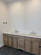 Bathroom with double vanity and dark tile patterned flooring