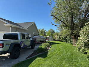 View of side of home featuring a lawn, stucco siding, and a shingled roof