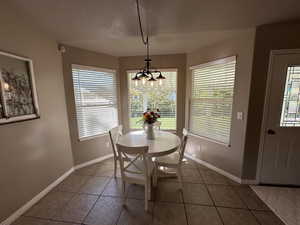 Dining room with a chandelier, tile patterned floors, and baseboards