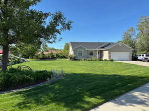Ranch-style house featuring an attached garage, a front yard, and driveway