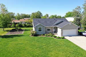 Ranch-style house with stone siding, an attached garage, driveway, a front lawn, and a shingled roof