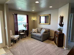Living area with light colored carpet, recessed lighting, and baseboards