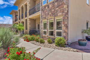 Doorway to property with stone siding, stucco siding, and a balcony