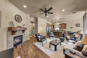 Living room with ceiling fan, arched walkways, dark wood-type flooring, recessed lighting, and a tiled fireplace