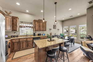 Kitchen featuring a sink, stainless steel dishwasher, light wood-style floors, light stone counters, and recessed lighting