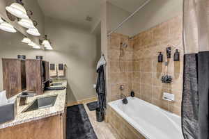 Full bathroom with tiled shower / bath, double vanity, and tile patterned flooring