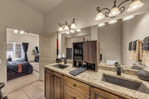 Ensuite bathroom featuring double vanity, tile patterned flooring, a ceiling fan, and a towering ceiling