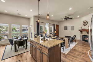 Kitchen with recessed lighting, open floor plan, light wood finished floors, a glass covered fireplace, and a ceiling fan