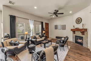 Living area featuring ceiling fan, a glass covered fireplace, recessed lighting, wood finished floors, and baseboards