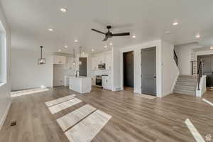 Unfurnished living room featuring baseboards, a ceiling fan, light wood finished floors, and recessed lighting