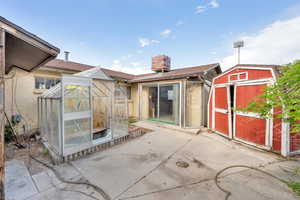 Back of house featuring a greenhouse, a patio, and a chimney