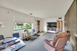 Carpeted living area featuring a textured ceiling