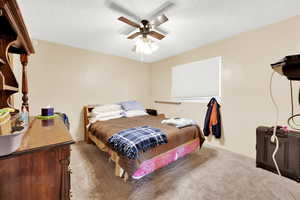 Bedroom featuring carpet, a textured ceiling, and ceiling fan