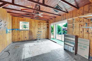 Unfurnished room with plenty of natural light, wooden walls, and a ceiling fan