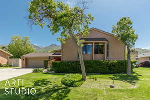 View of front of house with driveway, a mountain view, an attached garage, and a front yard