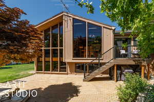 Rear view of property featuring a sunroom, a patio area, and stairs