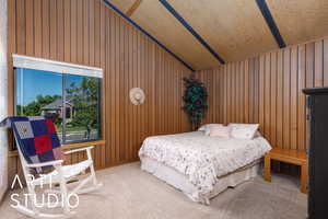 Carpeted bedroom featuring lofted ceiling and wood walls