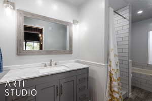 Full bathroom with vanity, a wainscoted wall, a bathtub, wood finished floors, and curtained shower