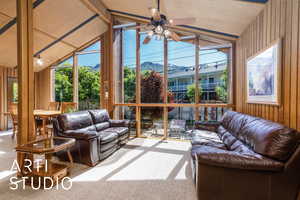 Sunroom / solarium with vaulted ceiling, wood walls, a mountain view, and carpet