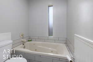 Full bath with toilet and a whirlpool tub