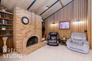 Carpeted living room with wooden walls, lofted ceiling, and a fireplace