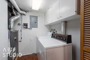 Laundry room with cabinet space, electric panel, washer and dryer, and tile patterned floors