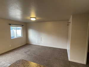 Carpeted empty room featuring baseboards and a textured ceiling