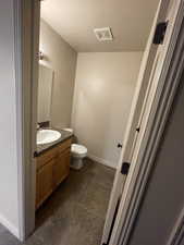 Half bath featuring vanity, toilet, tile patterned flooring, and a textured ceiling