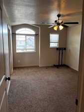 Spare room with carpet floors, ceiling fan, a textured ceiling, and baseboards