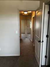 Hall with dark carpet and baseboards