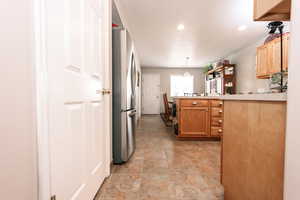 Kitchen featuring freestanding refrigerator, light countertops, recessed lighting, hanging light fixtures, and a peninsula