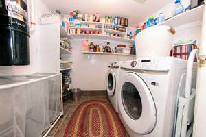 Washroom with washing machine and clothes dryer and dark tile patterned flooring