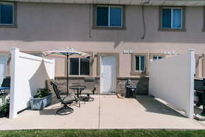 Rear view of property featuring a patio area, stucco siding, and stone siding