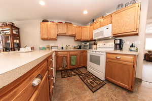 Kitchen featuring white appliances, light countertops, recessed lighting, dark stone finish flooring, and a sink