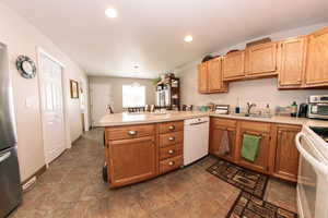 Kitchen with white appliances, a sink, a peninsula, light countertops, and recessed lighting