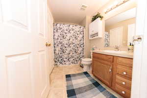 Full bathroom with vanity, tile patterned floors, toilet, and a shower with shower curtain