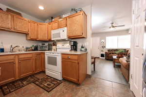 Kitchen featuring white appliances, a ceiling fan, light countertops, a sink, and recessed lighting
