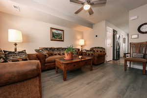 Living room featuring ceiling fan and dark wood finished floors