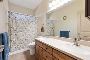 Bathroom with toilet, double vanity, tile patterned floors, and curtained shower