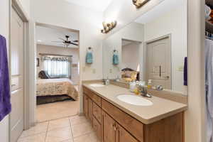 Ensuite bathroom featuring double vanity, tile patterned flooring, and a ceiling fan