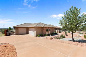 View of front facade featuring a tiled roof, stucco siding, an attached garage, concrete driveway, and stone siding