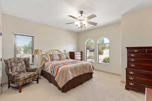 Bedroom featuring multiple windows, light colored carpet, baseboards, and a ceiling fan