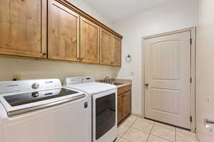 Laundry room featuring washing machine and clothes dryer, cabinet space, and light tile patterned floors