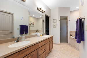Full bathroom featuring tile patterned flooring, a garden tub, a shower stall, double vanity, and a spacious closet